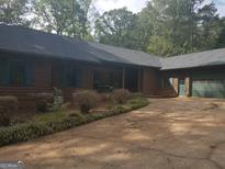 Ranch home with two car garage, brown siding, and mature landscaping at 2467 Highway 138 Sw, Conyers, GA 30094