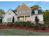 Charming two-story home boasts a brick and siding facade, complemented by a beautifully landscaped front yard and colorful flower beds at 5875 Windjammer Pt, Cumming, GA 30041