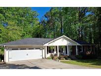 Charming single-story home with a two-car garage, front porch, and landscaped yard with mature trees in the background at 1898 Mornington Ln, Snellville, GA 30078
