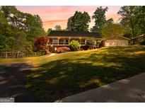 Charming ranch-style home with a welcoming porch and lush, landscaped front yard at sunset at 335 Winding Stream Trl, Hampton, GA 30228