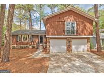 Charming two-story home featuring a two-car garage and a balcony, surrounded by lush trees at 5350 Rockbridge Rd, Stone Mountain, GA 30088