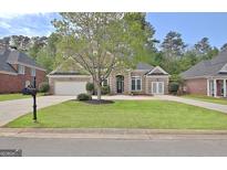 Charming brick home with a well-manicured lawn, two-car garage, and inviting front entrance at 1619 Cascade Overlook, Peachtree City, GA 30269