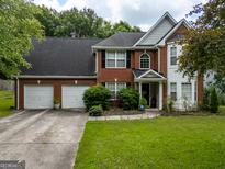 Traditional two-story brick home featuring a two-car garage and manicured front lawn at 345 S Magnolia Se Walk, Atlanta, GA 30349