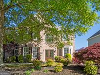 Charming brick home featuring a well-manicured lawn and mature trees offering shade and curb appeal at 630 Bluff Oak Ct, Roswell, GA 30076