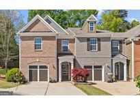 Charming townhome with a brick and gray exterior, a well-manicured lawn, and a two-car garage at 5260 Sherwood Way, Cumming, GA 30040