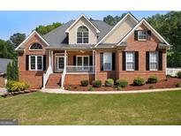 Charming brick home featuring a covered front porch, manicured landscaping, and black shutters at 1108 Sequoia Trl, Mcdonough, GA 30252