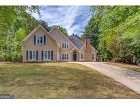 Beautiful two-story home featuring a well-manicured lawn and a long driveway leading up to the residence at 12340 Preserve Ln, Alpharetta, GA 30005