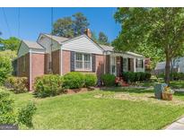 Charming brick home featuring a well-maintained lawn, mature trees, and classic black shutters at 1325 E Forrest Ave, East Point, GA 30344