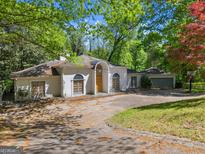 Unique single-story home with light colored stucco and an arched doorway, surrounded by mature trees at 3985 Randall Mill Nw Rd, Atlanta, GA 30327