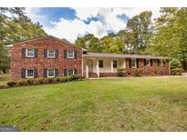 Charming brick home featuring dark shutters, lush green lawn, and mature trees at 8289 Lake View Ter, Riverdale, GA 30274