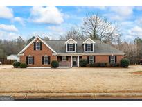Charming brick home featuring dormer windows, black shutters, and manicured landscaping at 115 Stewart Hollow Ln, Covington, GA 30016