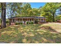 Charming single-story brick home with a cozy front porch, lush green lawn, and mature trees at 370 Merrydale Dr, Fayetteville, GA 30215