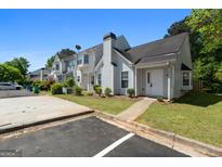 Inviting townhome exterior with manicured landscaping and ample parking on a clear, sunny day at 5882 Trent Walk Dr, Lithonia, GA 30038