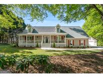 Charming single-Gathering home boasts a welcoming front porch, lush landscaping, and red shutters at 423 Bear Creek Trl, Hampton, GA 30228