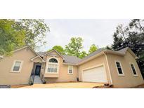Beige home featuring an attached garage, front yard, and well-manicured landscaping at 1252 Heritage Dr, Villa Rica, GA 30180