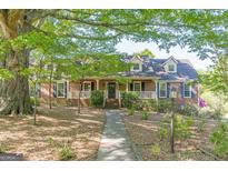 Charming brick home featuring a welcoming front porch and well-manicured landscaping under the shade of mature trees at 13819 Woolsey Rd, Hampton, GA 30228