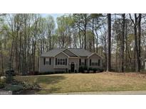 Charming single-story home with a well-manicured front lawn and classic curb appeal amongst a forest-like backdrop at 5930 Shannon Dr, Cumming, GA 30040
