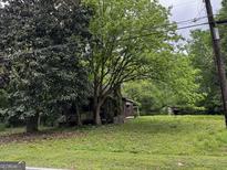 Rustic cabin-style home featuring mature trees and a charming stone chimney at 3935 Jailette Rd, South Fulton, GA 30349