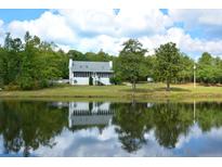 Scenic home exterior reflected in a serene pond surrounded by lush greenery and a bright, cloudy sky at 301 Spruill Bridge Rd, Temple, GA 30179