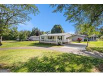 Charming one-story home with covered porch, carport and well-maintained lawn on a sunny day at 73 Highpoint Ln, Locust Grove, GA 30248