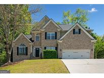 Charming two-story brick home with a well-manicured lawn and a two-car garage, set against a bright blue sky at 3338 Hackmatack Dr, Kennesaw, GA 30152