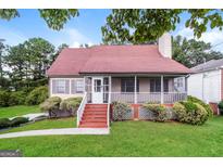 Charming home featuring a screened front porch, cozy landscaping, and a well-manicured lawn at 6024 S Deshon Ct, Lithonia, GA 30058