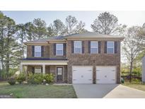 Charming two-story brick home featuring a two-car garage, inviting front porch, and manicured lawn at 1144 Bluecoat Cir, Hampton, GA 30228