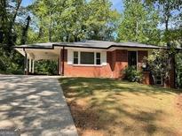 Charming one-story brick house with a carport and well-maintained front yard, nestled among mature trees at 1815 Dodson Sw Dr, Atlanta, GA 30311