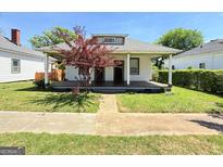 Charming single story home with a covered front porch and a small decorative tree in the front yard at 30 Poplar St, Porterdale, GA 30014