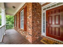 Charming front porch with brick facade, wood-look flooring, and a welcoming front door at 803 Baugh Springs Ln, Lawrenceville, GA 30044