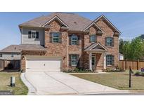 Charming two-story brick home with a manicured lawn and a spacious driveway at 7435 Ansley Park Way, Cumming, GA 30028