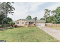 Charming single-story home with a well-maintained lawn, a front porch, and a two-car garage at 15 Pine Run Rd, Carrollton, GA 30116