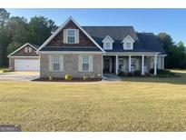 Charming brick home features an attached garage, inviting front porch with rocking chairs, and a well-manicured lawn at 30 Scouts Ridge Dr, Covington, GA 30016