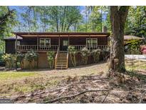 Rustic cabin-style home featuring a charming front porch and mature trees on a wooded lot at 20 King Pl, Stockbridge, GA 30281