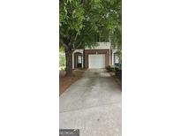 Brick townhome with a one car garage, mature trees, and a concrete driveway at 2867 Snapfinger Mnr, Decatur, GA 30035