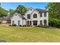 Charming two-story white home with black trim, lush lawn, and mature trees at 608 Bellenden Dr, Peachtree City, GA 30269
