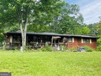 Charming single-story home with a large front yard, a covered porch and a beautiful garden at 5780 Hill Rd, Powder Springs, GA 30127