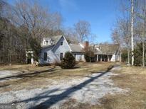 View of a two-story home with a brick chimney and a gravel driveway surrounded by trees at 526 Mount Carmel Church Rd, Temple, GA 30179