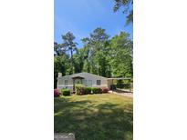 Charming home features a covered front porch, well-manicured lawn, mature trees, and convenient covered parking at 1973 Niskey Lake Sw Rd, Atlanta, GA 30331