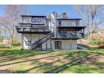 Expansive backyard view features a home with a multi-level deck, mature trees, and a lush lawn at 5284 Silver Creek Sw Dr, Lilburn, GA 30047