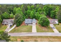 An aerial view showcases this single-Gathering home, nestled in a wooded neighborhood with a well-manicured lawn at 563 Deadwood Trl, Locust Grove, GA 30248