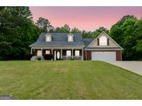 Charming single-story home featuring a brick facade, inviting porch, and attached two-car garage at 563 Deadwood Trl, Locust Grove, GA 30248