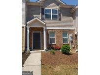 Charming two-story townhouse featuring a brick facade, a welcoming front porch, and a well-maintained landscaped yard at 6153 Oakley Rd, Union City, GA 30291