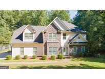 Beautiful home featuring stone and siding exterior, manicured lawn, and mature trees at 1231 Hillview Rd, Hampton, GA 30228