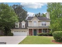 Charming two-story home features a manicured lawn, brick accents, and an attached two-car garage at 179 Parkside Dr, Stockbridge, GA 30281