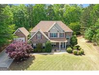 Beautiful two-story home with a stone and vinyl exterior, lush lawn, and mature trees at 21 Highbush Ct, Sharpsburg, GA 30277