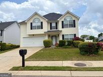 Charming two-story home features a well-manicured lawn and an attached two-car garage at 1130 Ivey Ln, Mcdonough, GA 30253