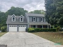 Two-story home with a gray exterior, two-car garage, and well-maintained landscaping at 716 Wilkes Dr, Loganville, GA 30052