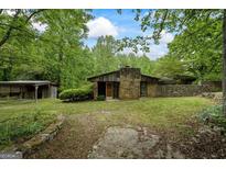 Charming single-story home with a stone facade, wood accents, and a covered storage building surrounded by lush greenery at 5493 Alexanders Lake Sw Rd, Stockbridge, GA 30281