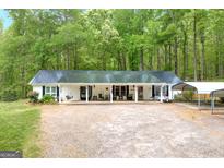 Charming single-story home featuring a metal roof, covered porch, and ample parking at 7616 Nicholson Rd, Cumming, GA 30028